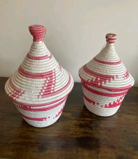 A pair of conical lidded storage baskets woven in cream and rose