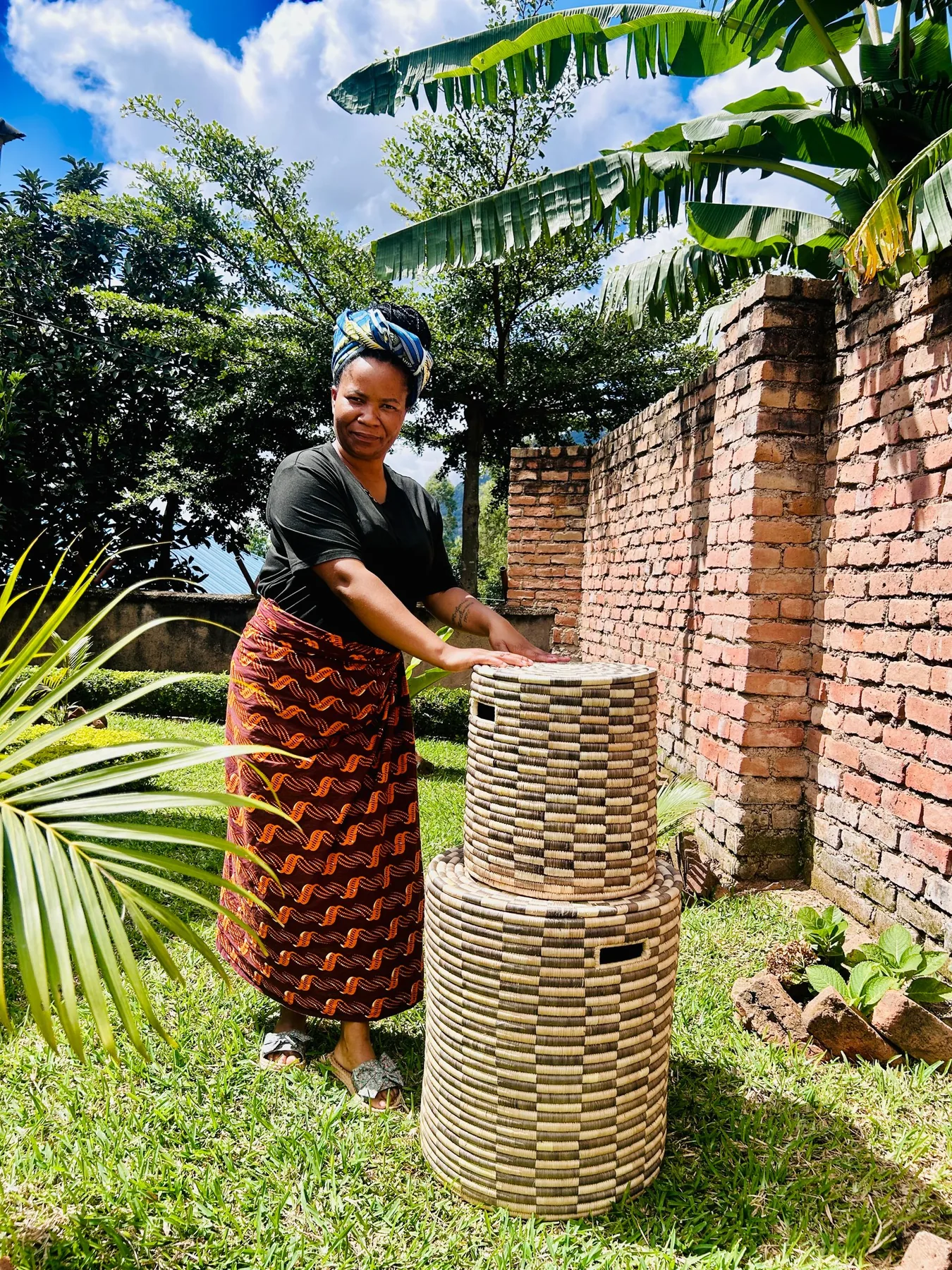 A weaver with two completed lidded hampers in a garden