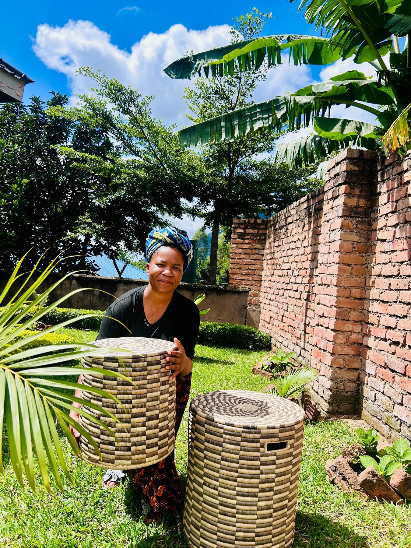 A weaver lifting a tall coiled hamper worked in a checkerboard pattern